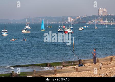 Pesca alla spiaggia di pescatori nell'estuario del Tamigi al largo di Shoeburyness, Southend on Sea, Essex, Regno Unito. Barche al largo di Thorpe Bay. Skyline della città di Southend. Persone in canoe Foto Stock