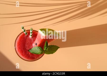 Cocktail di anguria guarnire la menta sul beige naturale con l'ombra soleggiata. Foto Stock