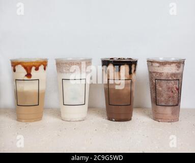 Bevande fredde al cioccolato in tazze di plastica affiancate, fondo bianco Foto Stock