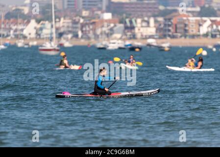 Bambini che pagaiano una XQ Max Vulcano stand up paddle board nell'estuario del Tamigi al largo di Thorpe Bay, Southend on Sea, Essex, Regno Unito. Inginocchiati, con kayak per tutta la famiglia Foto Stock