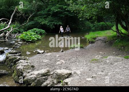 Due giovani ragazze che camminano lungo UN ruscello vicino a Milldale nel distretto di picco Derbyshire Inghilterra Regno Unito Foto Stock