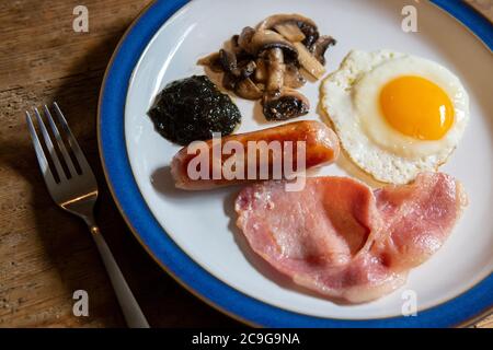 Piatto con una colazione completa di uova, salsicce, pancetta, funghi e pane alla lavanda Foto Stock