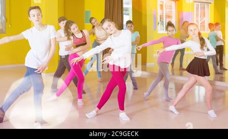 Il gruppo di formazione tweens movimenti di danza moderna in coreografia di classe con trainer femmina Foto Stock