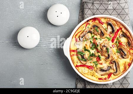 Frittata con funghi e pepe dolce su un tavolo di legno grigio. Foto Stock