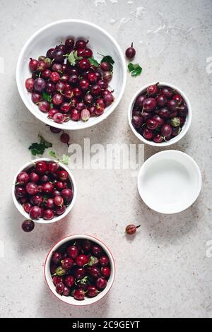 Frutti maturi di frutti rossi in ciotole bianche su uno sfondo di pietra chiaro. Foto Stock