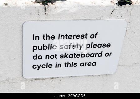 Un cartello che dice 'nell'interesse del pubblico sicuro, non fare skateboard o in bicicletta in questa zona'. Foto Stock