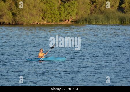 Donna anziana fuori pagaiando da lei in anticipo Mattina in estate su Clearlake California come lei impara Foto Stock