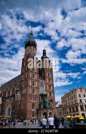 Cracovia, Polonia - 12 luglio 2020: Immagine verticale della Basilica di Santa Maria è una chiesa gotica in mattoni adiacente alla Piazza del mercato principale contro la drammatica cl Foto Stock