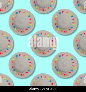 Cappello di paglia con nastro e pompon multicolore. Motivo senza cuciture su sfondo blu. Concetto estivo o di spiaggia. Foto Stock