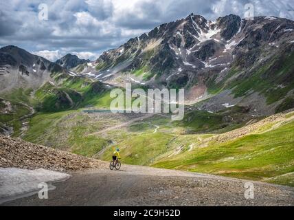 La mountain bike, nei suoi primi anni cinquanta, corre su strade alpine in ghiaia in alta montagna, Serfaus, Tirolo, Austria Foto Stock