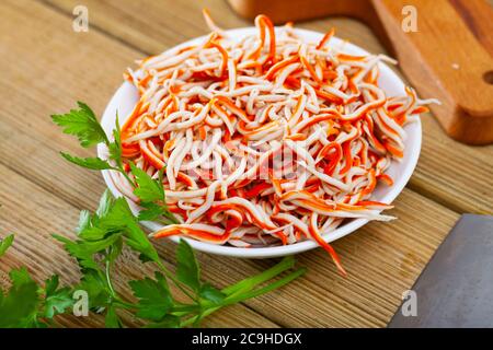 Ciotola con gustoso antipasto di surimi grattugiato su un tavolo di legno Foto Stock