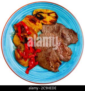 Bistecche di manzo mediamente rare con contorno vegetale di patate al forno e peperone. Isolato su sfondo bianco Foto Stock