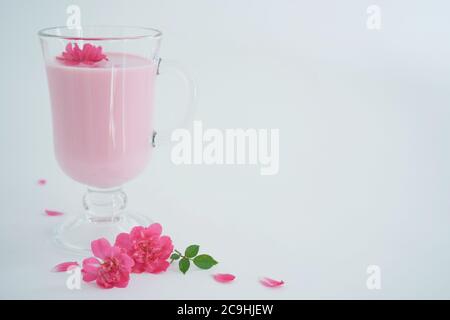 Latte di luna di rosa per un sonno migliore con spazio di copia. Ayurveda bevanda calda consumata prima di letto. Bello in caso di insonnia. Sfondo bianco, primo piano. Foto Stock
