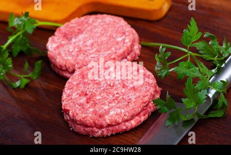 Tagli di carne grezza per hamburger su superficie di legno Foto Stock