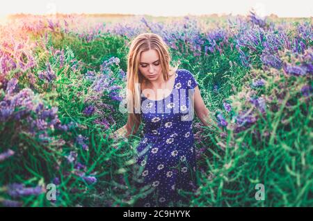 La giovane bionda europea snella cammina su erba alta Foto Stock