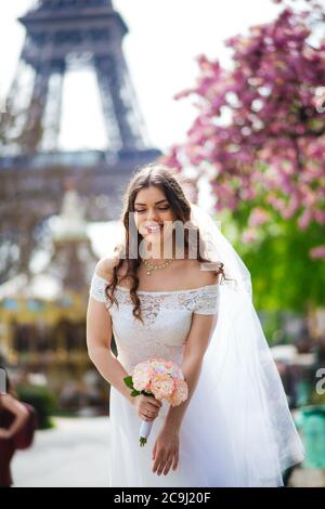 Bella sposa in ricco abito da sposa vortici sulla piazza prima della Torre Eiffel Foto Stock