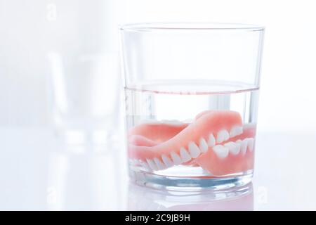 Dentures in un bicchiere d'acqua. Foto Stock