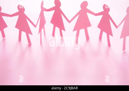 Figure femminili della catena di carta con taglio rosa su sfondo bianco. Foto Stock