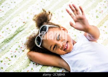Ragazza sdraiata su coperta nel parco, sorridente, ritratto. Foto Stock