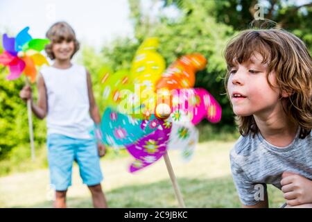 Ragazzo che soffia mulino a vento di carta multicolore. Foto Stock