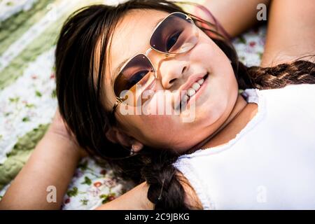 Ragazza sdraiata su coperta nel parco, sorridente, ritratto. Foto Stock