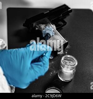 Tecnico forense che esamina l'arma, alla ricerca di impronte digitali. Laboratorio di scienze forensi. Foto Stock