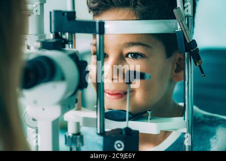 Oftalmologo che esamina gli occhi del ragazzo con una lampada a fessura . Foto Stock