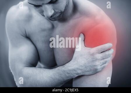 Primo piano immagine di un maschio che tiene la spalla dolorosa. Foto Stock