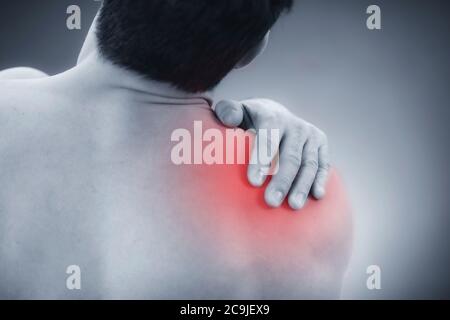 Primo piano immagine di un maschio che tiene la spalla dolorosa. Foto Stock