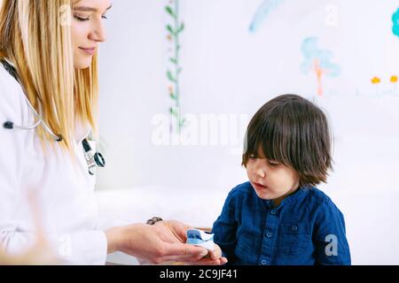 Pediatra che misura l'ossigeno nel sangue e il ritmo cardiaco con pulsossimetro. Foto Stock