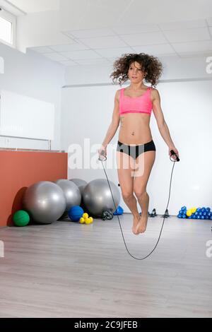 Donna che salta corda in palestra. Foto Stock