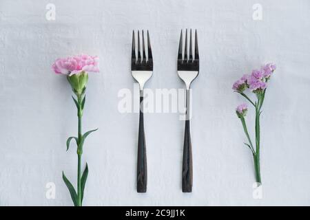due forchetta d'argento identiche con garofano rosa e fiore viola per il servizio di ristorazione sfondo Foto Stock