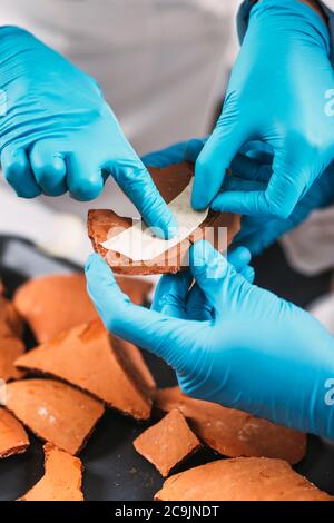 Archeologi che ricostruiscono le ceramiche rotte in laboratorio. Foto Stock