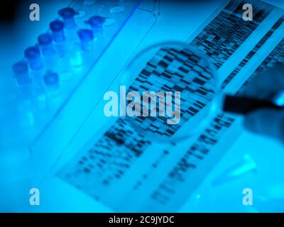 Scienziato che utilizza una lente di ingrandimento per visualizzare le striature su un profilo di DNA (acido desossiribonucleico) accanto ai campioni. Foto Stock