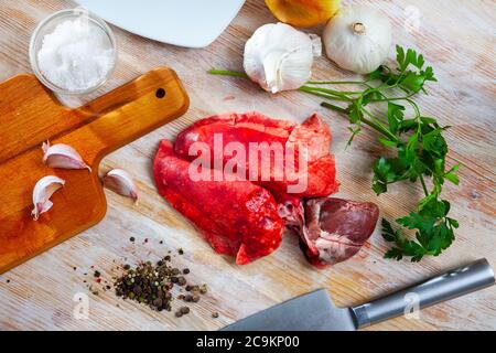Ingredienti per cucinare. Polmoni grezzi di montone e cuore con cipolla, aglio, spezie ed erbe su tavola di legno Foto Stock