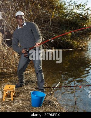 Emotional ritratto di uomo africano tirando con asta di pescare sul fiume Foto Stock