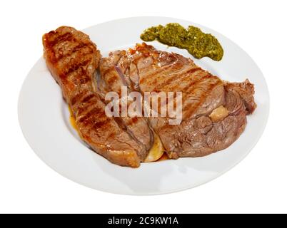 Bistecca di manzo mediamente rara con pesto piccante servita su piatto bianco. Isolato su sfondo bianco Foto Stock