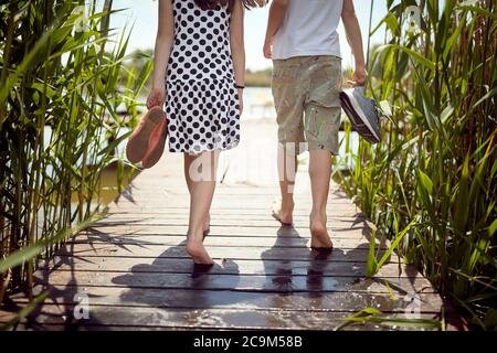 Fratello e sorella si tolsero le scarpe sul molo in una giornata di sole Foto Stock