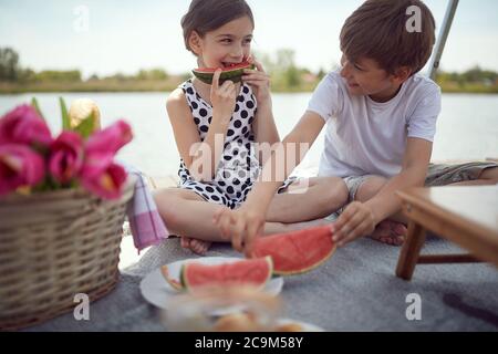 Felice fratello e sorella godere di anguria su un picnic sul lago Foto Stock