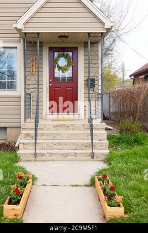 Porta rossa luminosa e vibrante su un lato beige; porta della facciata anteriore della casa semplice Foto Stock