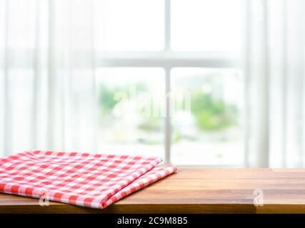 Tessuto rosso, panno su tavolo in legno su finestra sfocata in sfondo mattina. Per il montaggio del prodotto display o design chiave layout visivo. Foto Stock