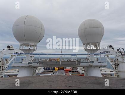 Radomi di comunicazione satellitare sul ponte superiore di una nave sismica nel Mare del Nord, con attrezzatura sismica immagazzinata qui sotto. Foto Stock