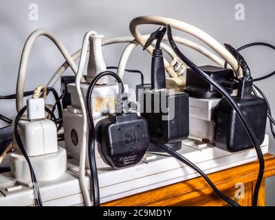 Un'alimentazione elettrica a 240 volt, probabilmente non sicura e sovraccarica, con un caos di più spine, prese, prolunghe, fili e cavi del Regno Unito. Foto Stock