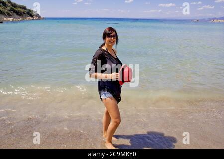 bella giovane donna in un cappello rosso sulla spiaggia Foto Stock