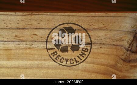 Timbro di riciclaggio stampato su scatola di legno. Simbolo di riciclo, frecce, materiali riciclabili, protezione ambientale e concetto di protezione della terra. Foto Stock