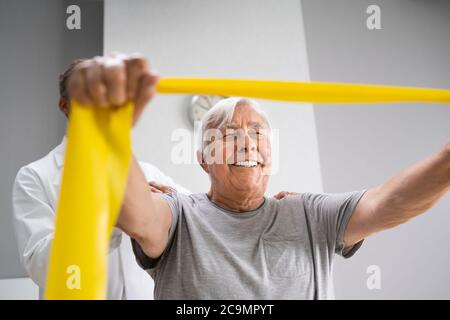 Paziente con terapia fisica che utilizza bande di fisioterapia per la riabilitazione Foto Stock