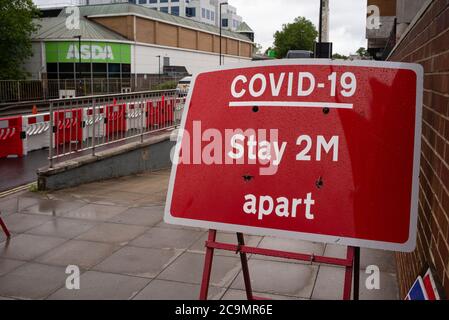 Covid-19 virus rimanere 2 m Apart strada segno fuori Asda nella città di Southampton Inghilterra. Foto Stock