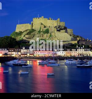 Mont Orgueil Castello che domina il porto e illuminato di notte, Gorey, Jersey, Regno Unito Foto Stock