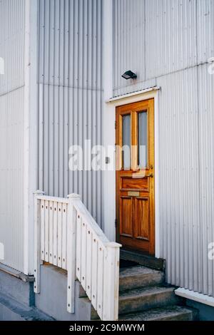 Una porta di legno marrone con finestre in un edificio con pareti e scalini bianchi. Foto Stock