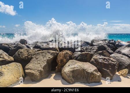 Una spiaggia in Barbados con onde che si infrangono su rocce Foto Stock